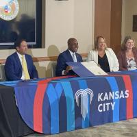 KC Mayor Quinton Lucas displaying the signed agreement sitting at a table with project partners. Pictured left to right, Charlie Shields, Mario Vasquez, Quinton Lucas, Valerie Huhn and Caroline Coulter.